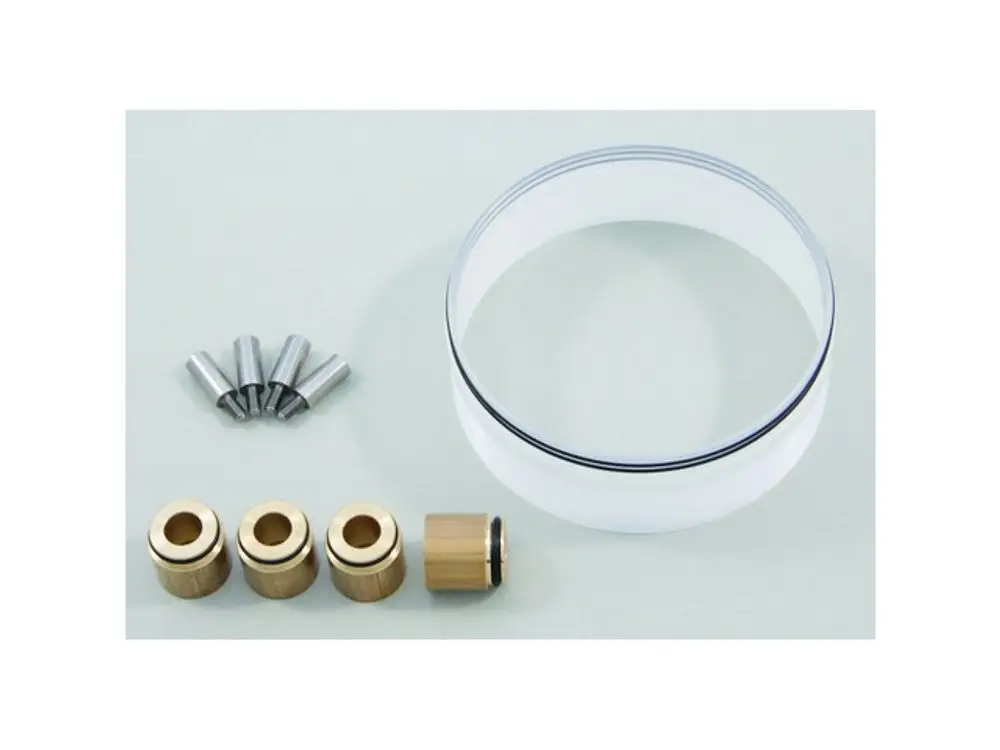 Ideal Standard produktspezifische Teile, darunter Metall- und Kunststoffkomponenten, angeordnet auf einer hellen Fläche.